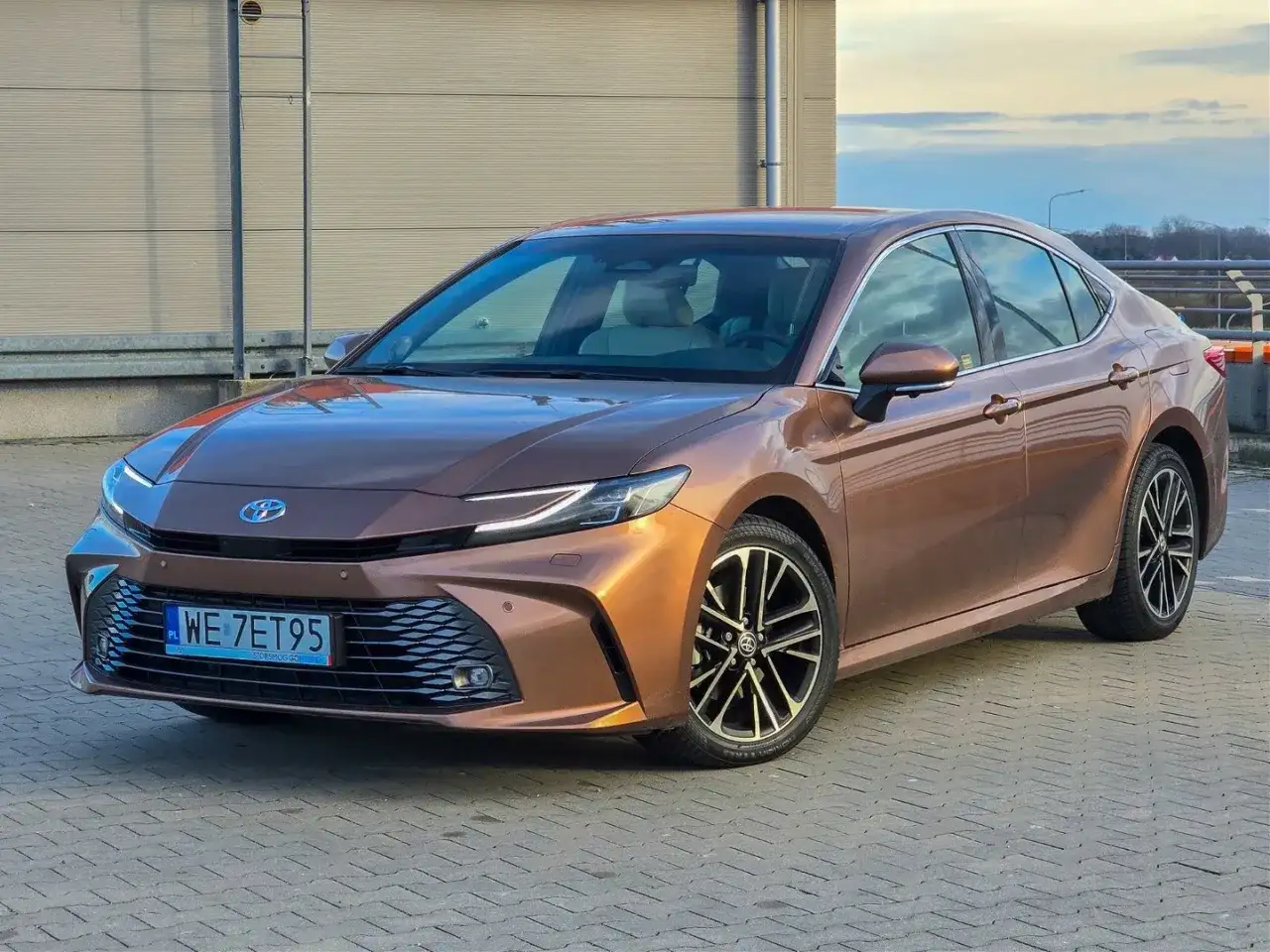 Brązowa Toyota Camry 2.5 Hybrid lśni w słońcu, gotowa na podróż.