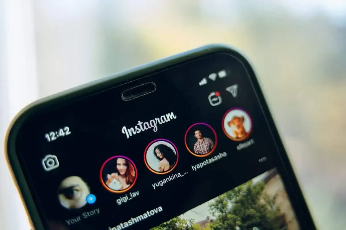 Telefon z otwartym Instagramem, pokazujący profile znajomych. Dowiedz się, jak udostępnić czyjąś relację na swoim IG.