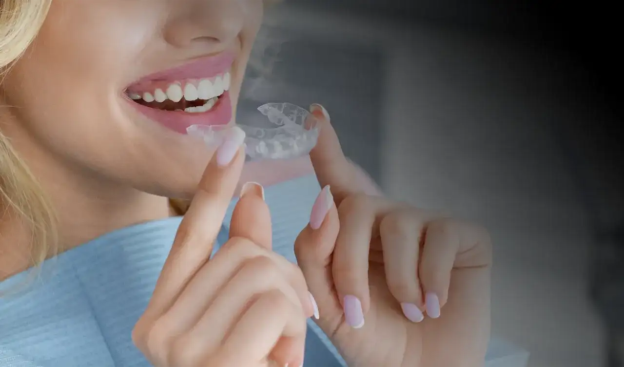 Uśmiechnięta kobieta z idealnymi zębami trzyma przezroczysty aparat. Sprawdź, jaka jest **invisalign cena** i zacznij swoją metamorfozę!