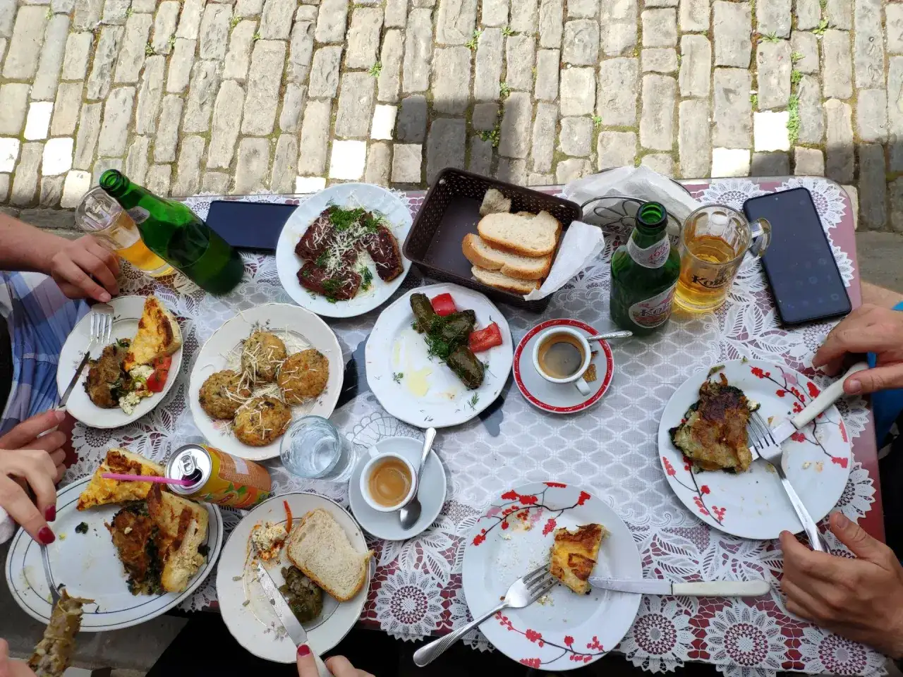 Pyszne albania jedzenie: mięso, gołąbki, placki i pieczywo na stole, obok piwo i kawa.