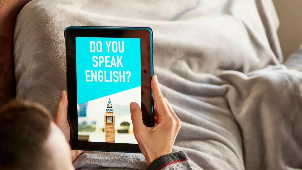 Osoba korzysta z aplikacji do nauki angielskiego na tablecie. Na ekranie widnieje pytanie "DO YOU SPEAK ENGLISH?" i miniatura Big Bena.