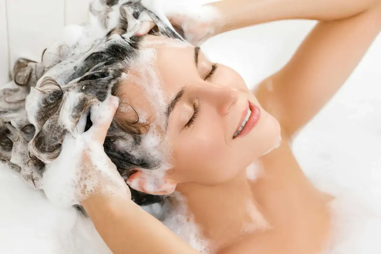 Donna con capelli schiumosi, ignara che l'ammonium lauryl sulfate fa male.