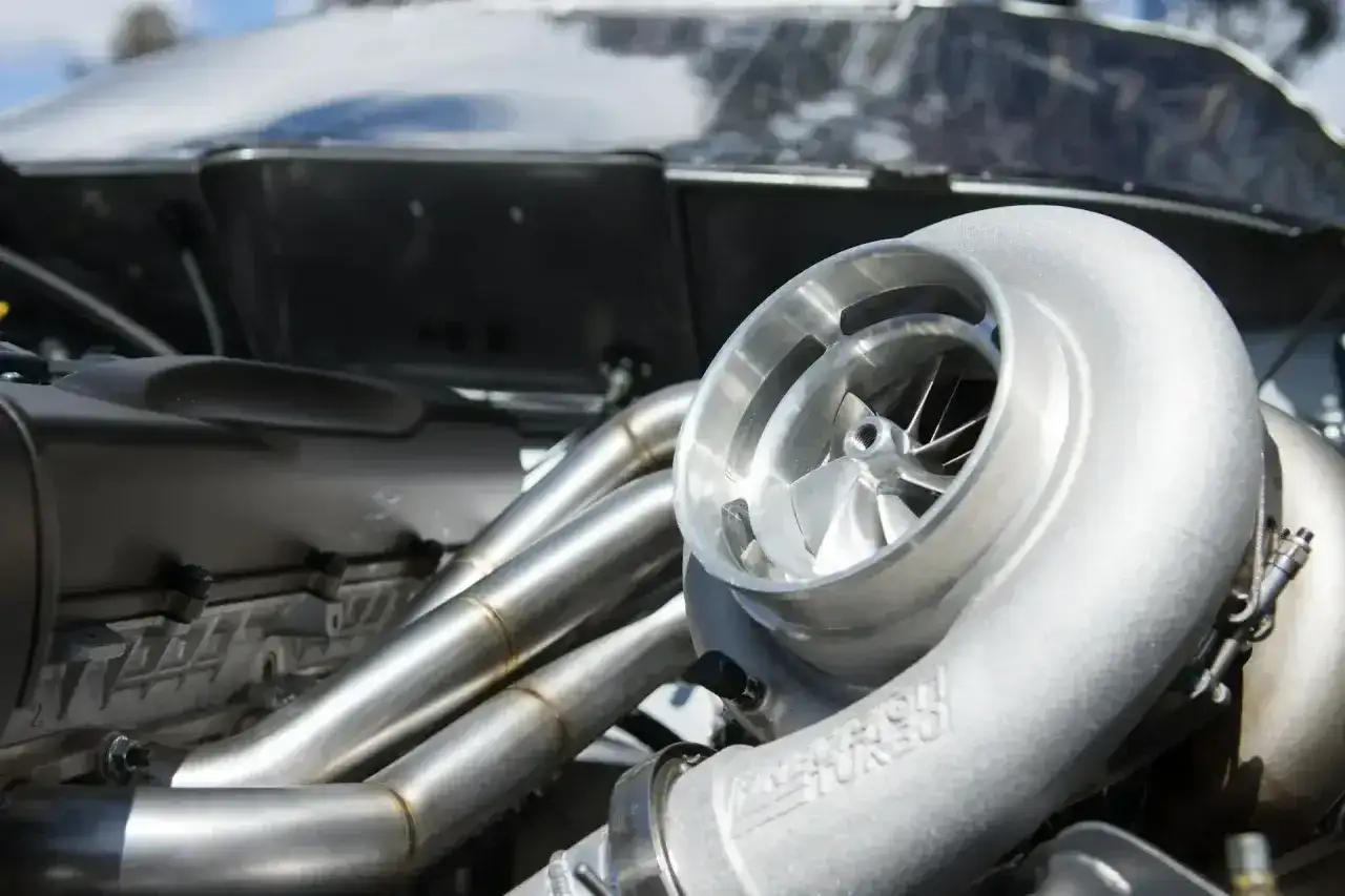 Błyszcząca turbosprężarka p0299 z wirnikiem i kolektorem wydechowym w silniku wyścigowym.