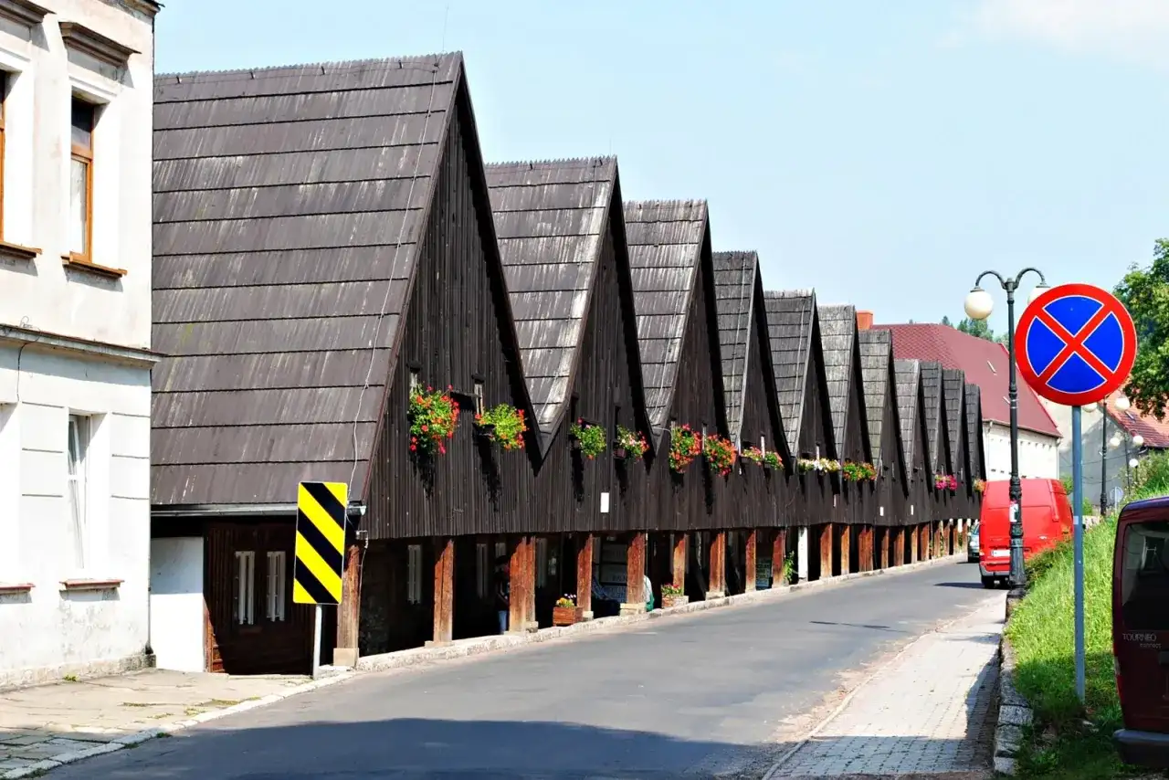 Rząd drewnianych domów z charakterystycznymi spiczastymi dachami i kwitnącymi balkonami. Chełmsko Śląskie atrakcje zachwycają unikalną architekturą.