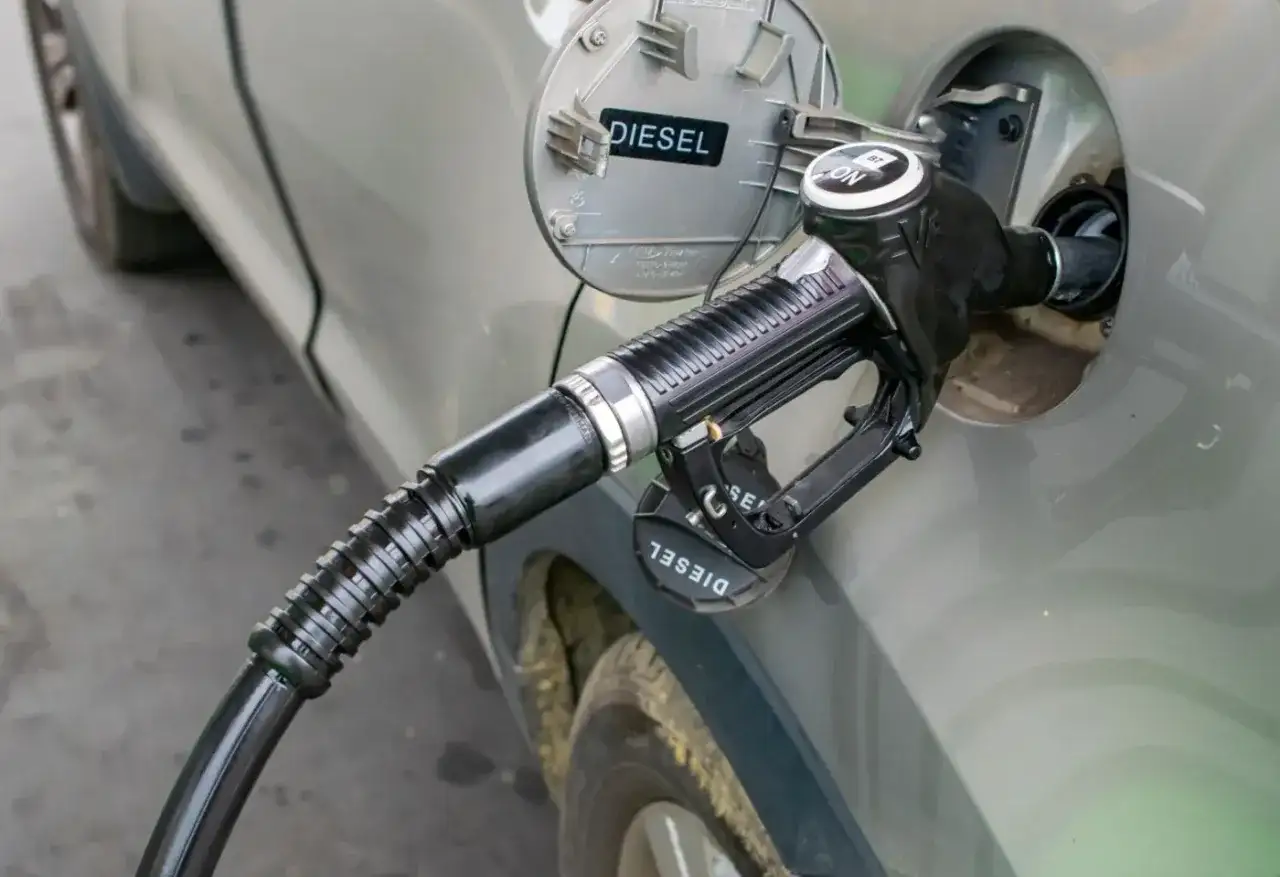 Tankowanie diesla. Zbliżenie na pistolet paliwowy wlewu paliwa samochodu. Informacja o rodzaju paliwa "DIESEL" jest widoczna.