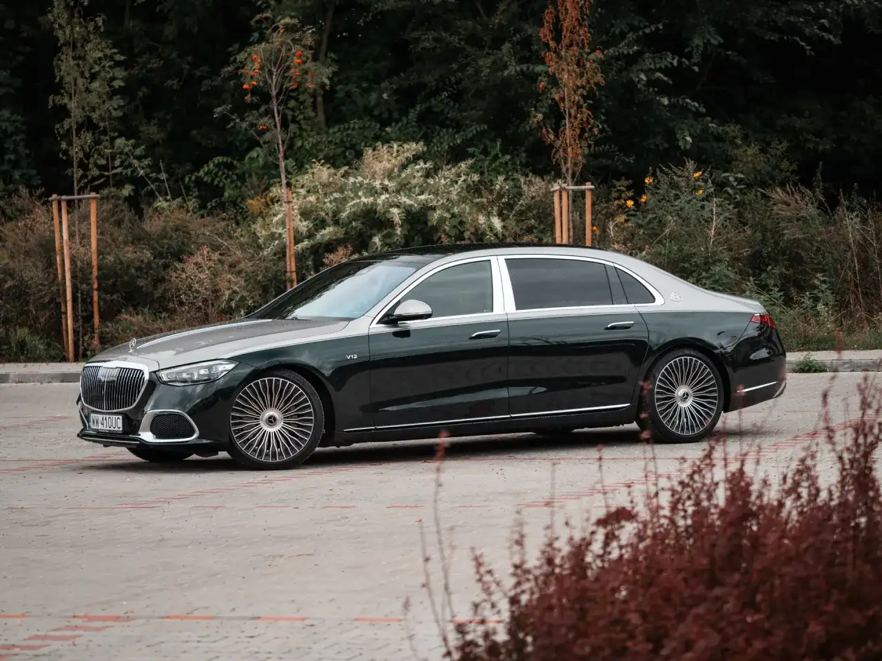 Elegancki Mercedes-Maybach S680 w ciemnozielonym kolorze z dwukolorowym nadwoziem, zaparkowany na tle zieleni.