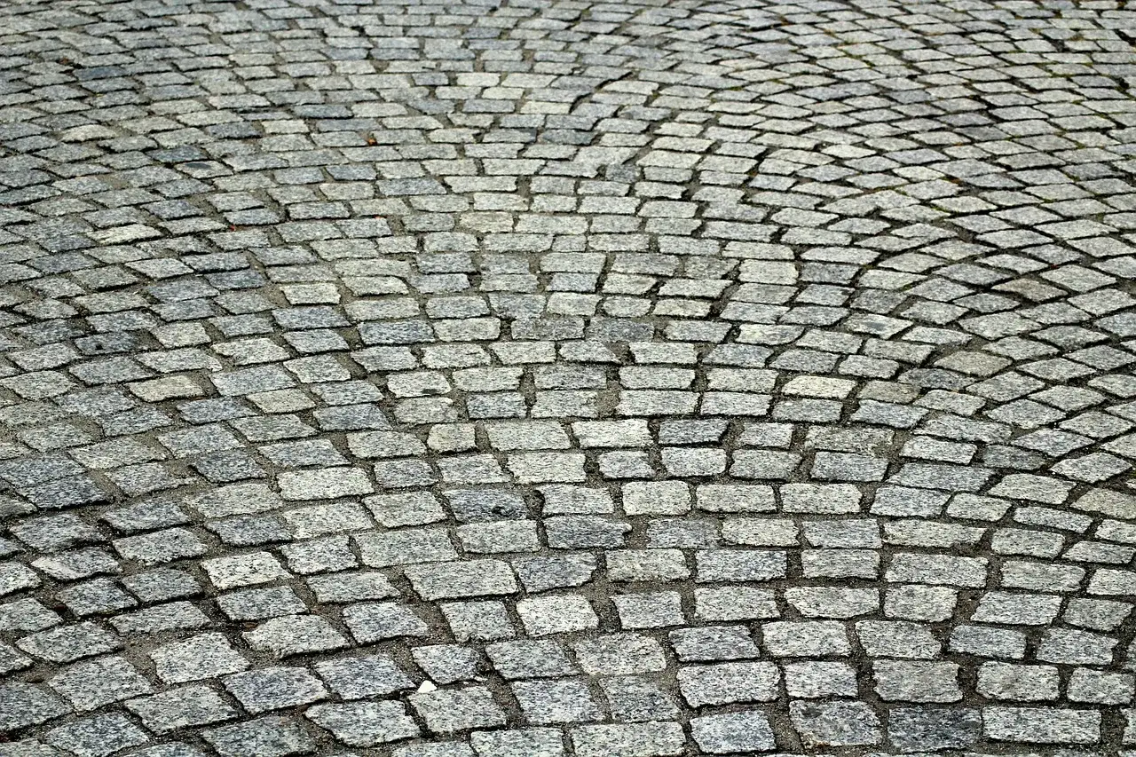Szara kostka granitowa ułożona łukiem. Dokładne ile kostki granitowej na m2 zależy od jej wymiarów.
