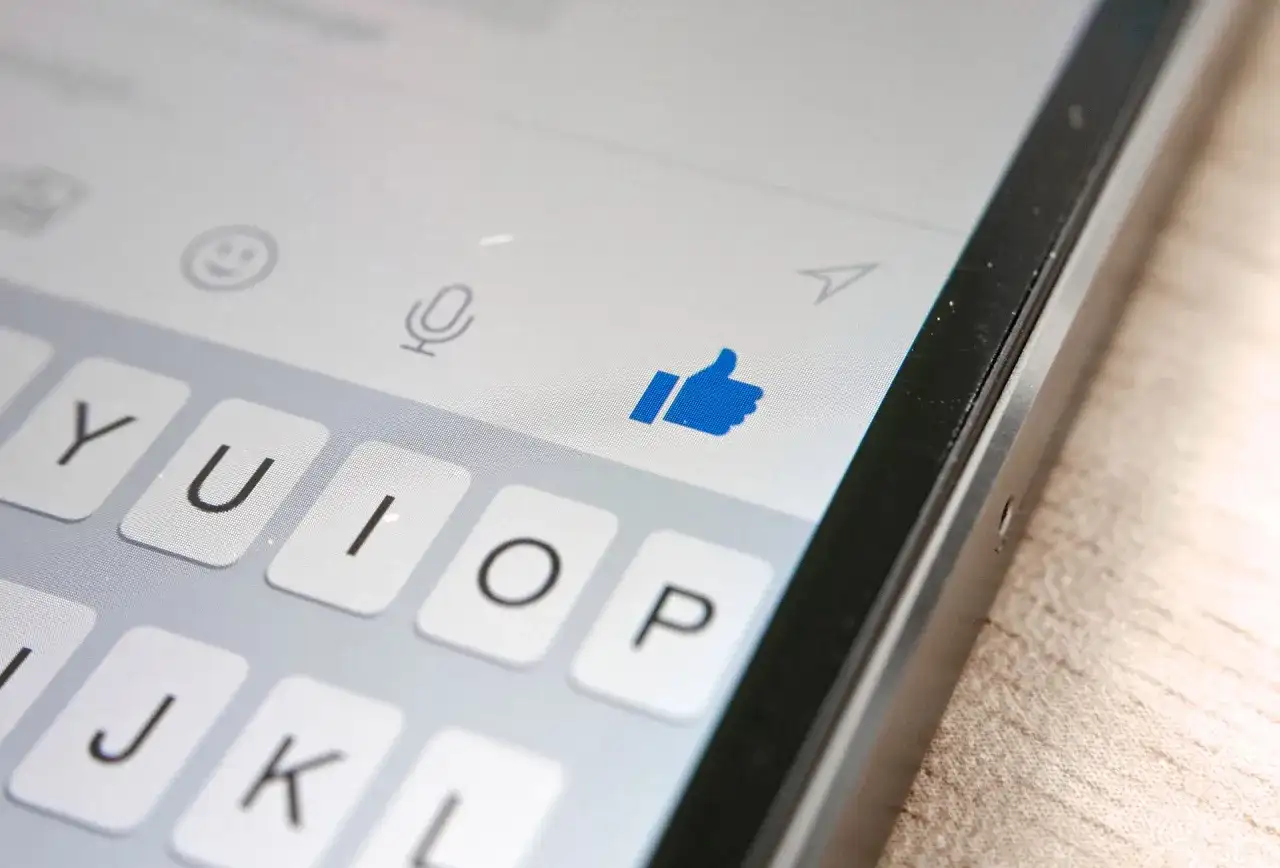 Kciuk w górę na ekranie telefonu, pokazujący, jak działa aktywność na Messengerze. Klawiatura i ikony czatu.