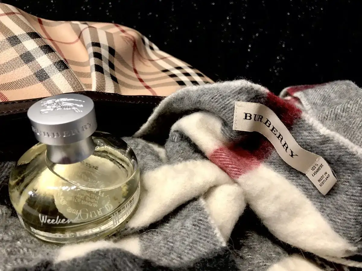 Flakon perfum Burberry Weekend obok szarego szala z charakterystyczną kratą. Idealny zestaw na weekend.