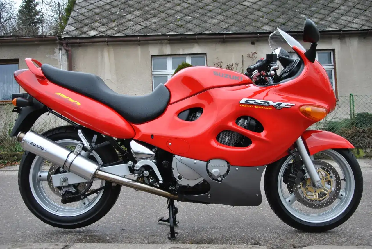 Czerwony motocykl Suzuki GSX-F 600 z czarnym siedzeniem, zaparkowany przed budynkiem.