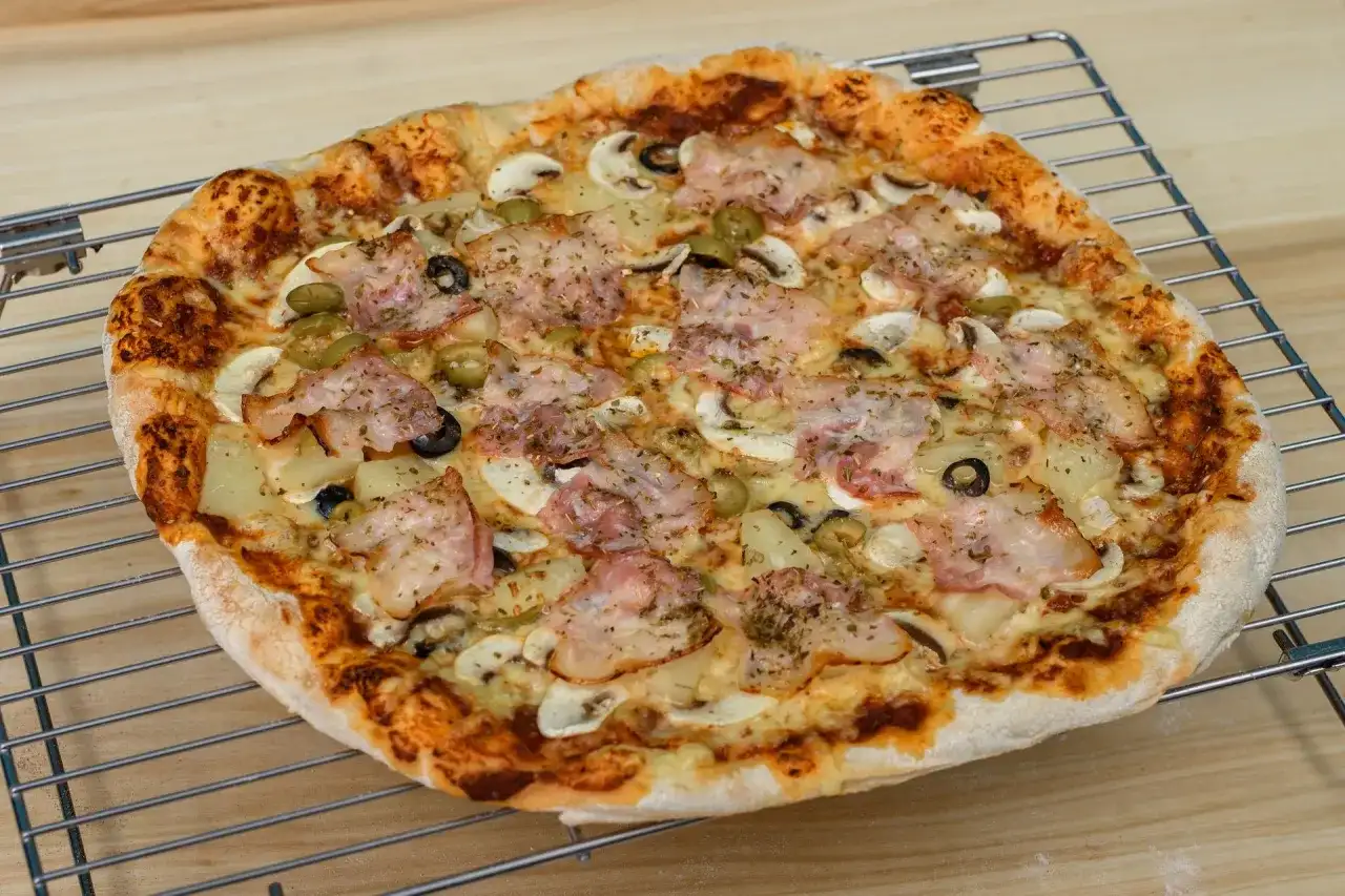 Pyszna pizza z szynką, pieczarkami, oliwkami i ananasem. Idealna na rodzinny obiad, zastanawiasz się ile piec pizze?