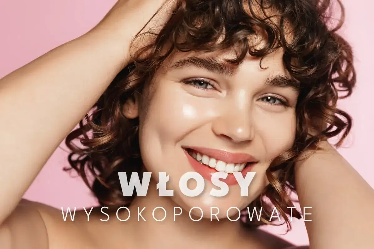 Uśmiechnięta kobieta z kręconymi, **wysokoporowatymi włosami** w odcieniach brązu, dotyka dłonią swoich loków.