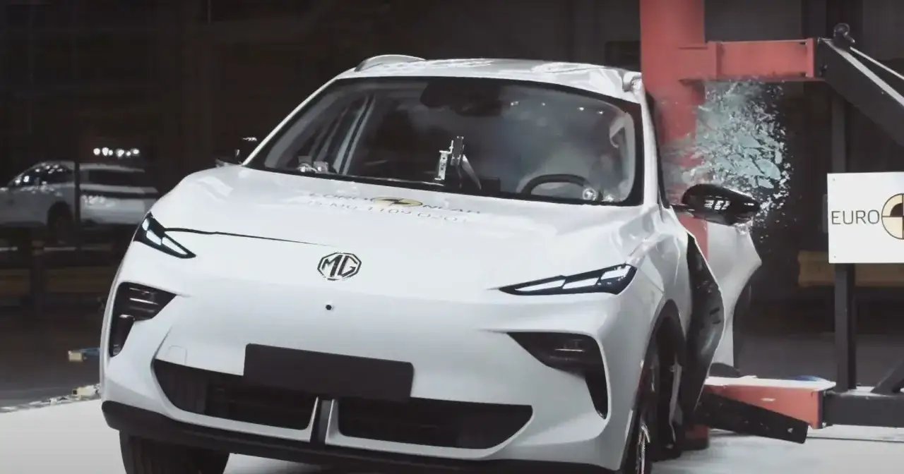 Białe chinskie auto MG po teście zderzeniowym Euro NCAP, z rozbitą szybą i uszkodzonymi elementami.