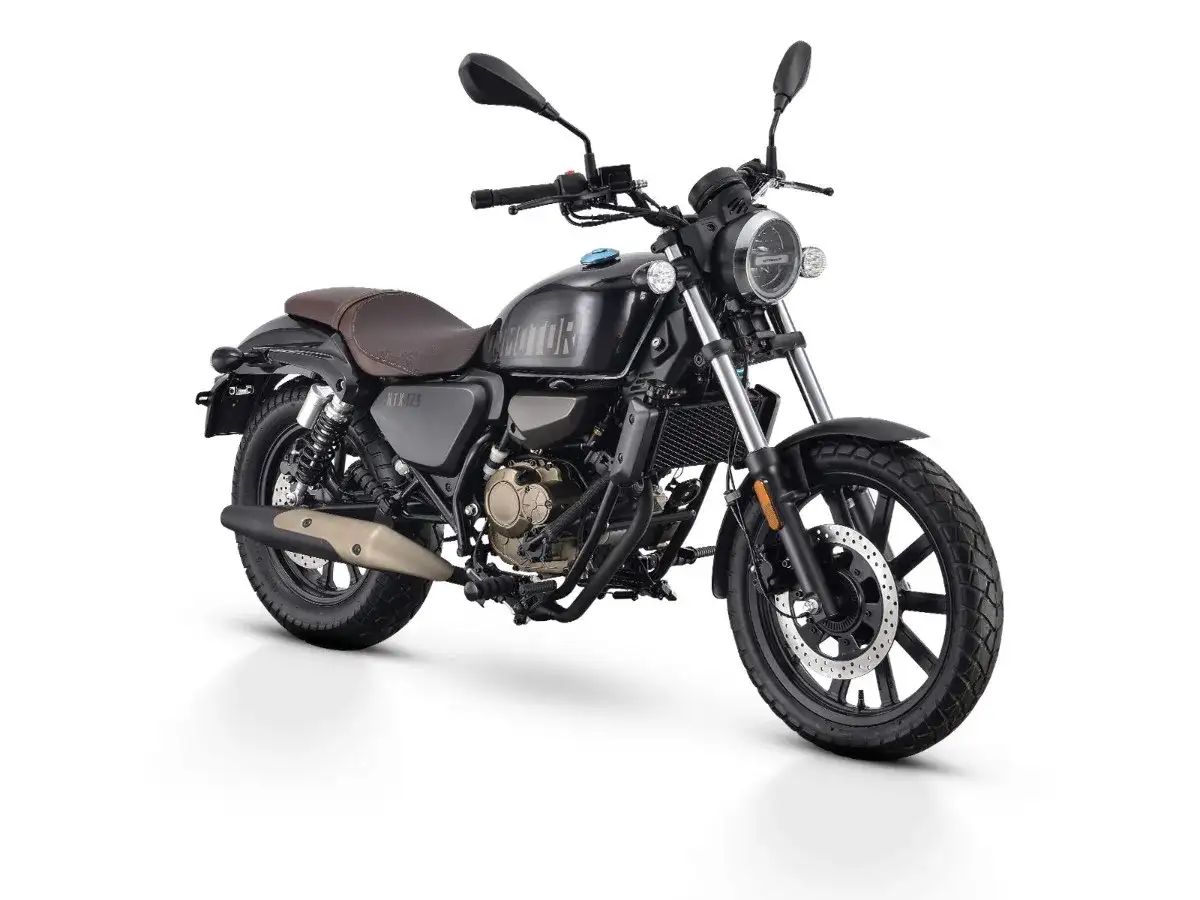 Czarny motocykl w stylu retro, z brązowym siedzeniem i złotymi elementami silnika. To najmocniejsze 125 na b, gotowe na każdą drogę.