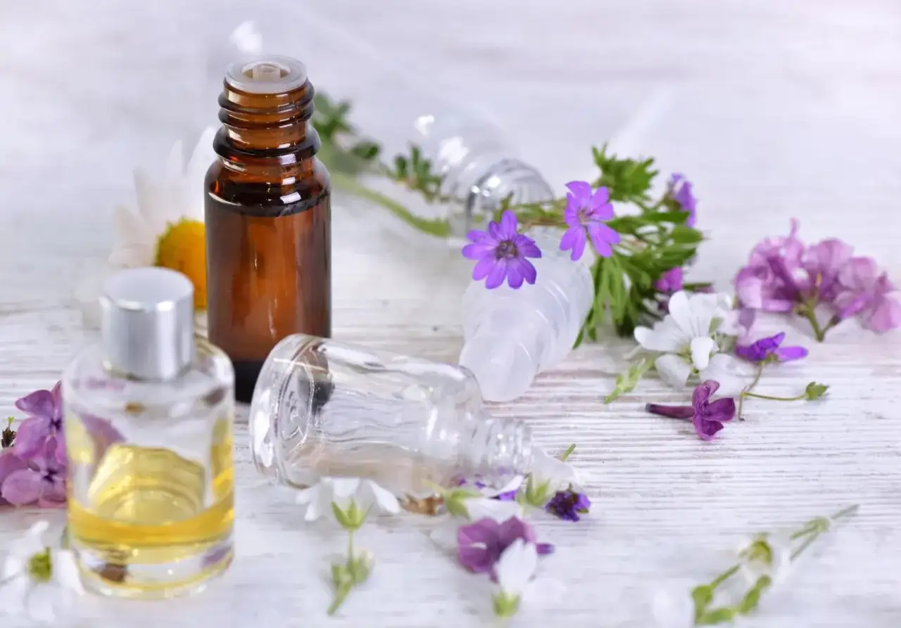 Aromaterapia: amol na co pomaga? Butelki z olejkami i kwiaty sugerują relaks i ukojenie.