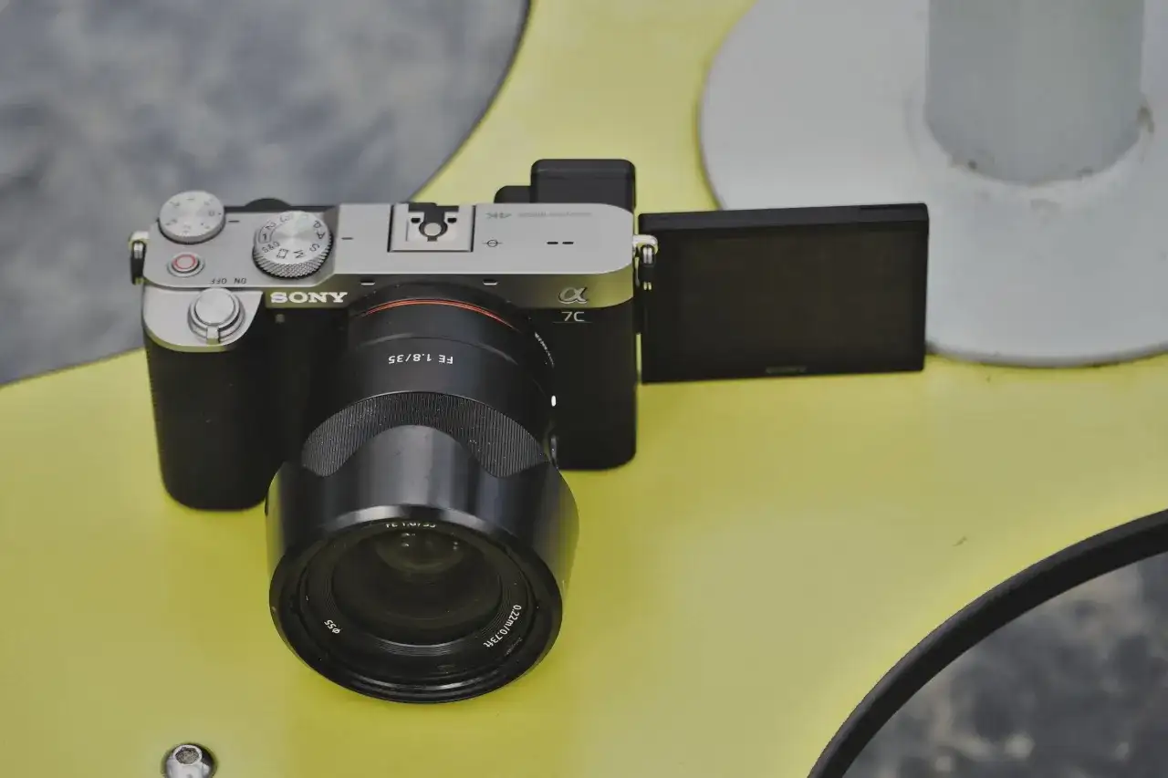 Aparat Sony a7c z obiektywem FE 1.8/35 na żółtym tle.
