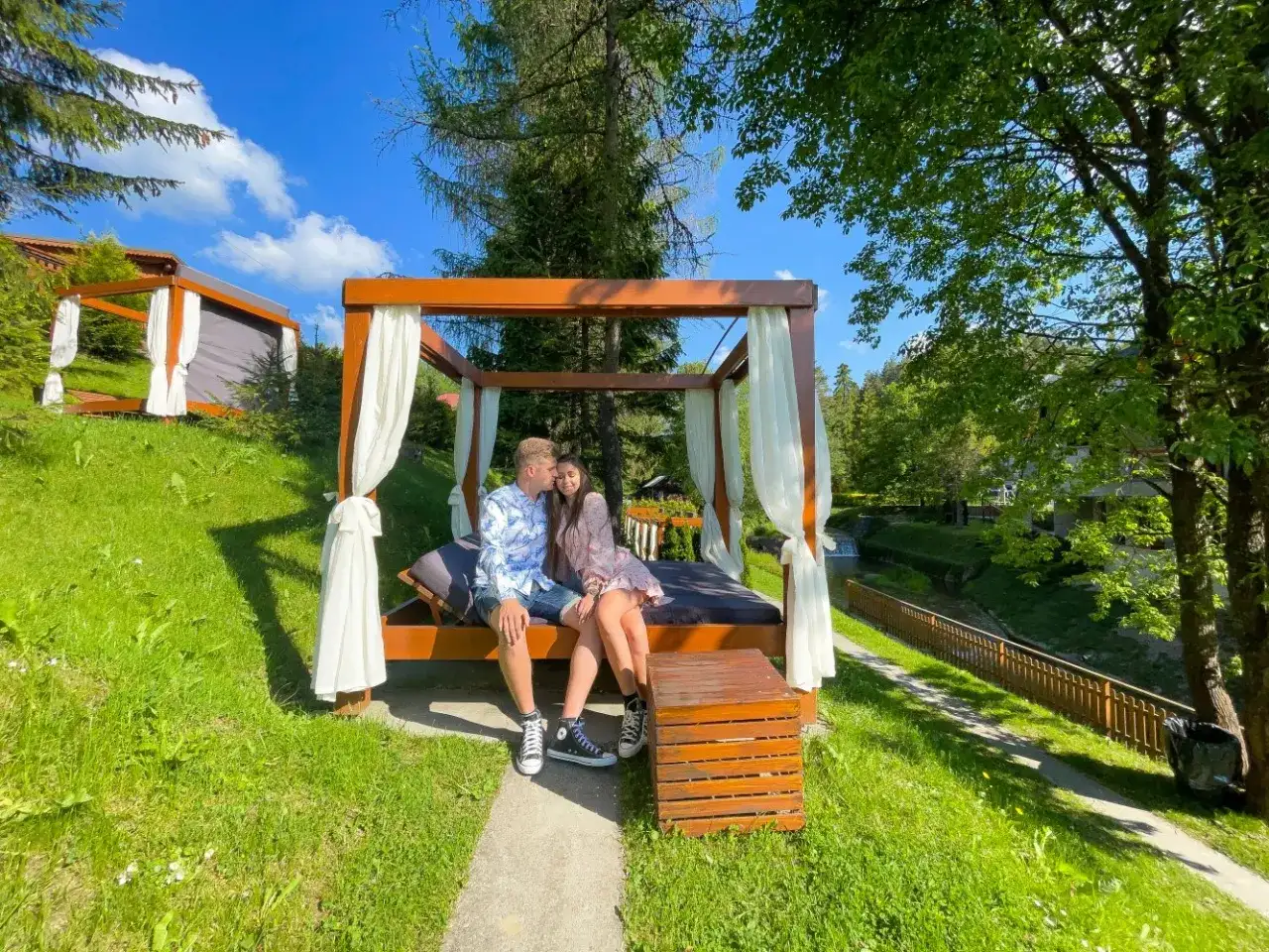 Para spędza romantyczny last minute weekend dla dwojga na łóżku pod baldachimem, otoczona zielenią i strumykiem.