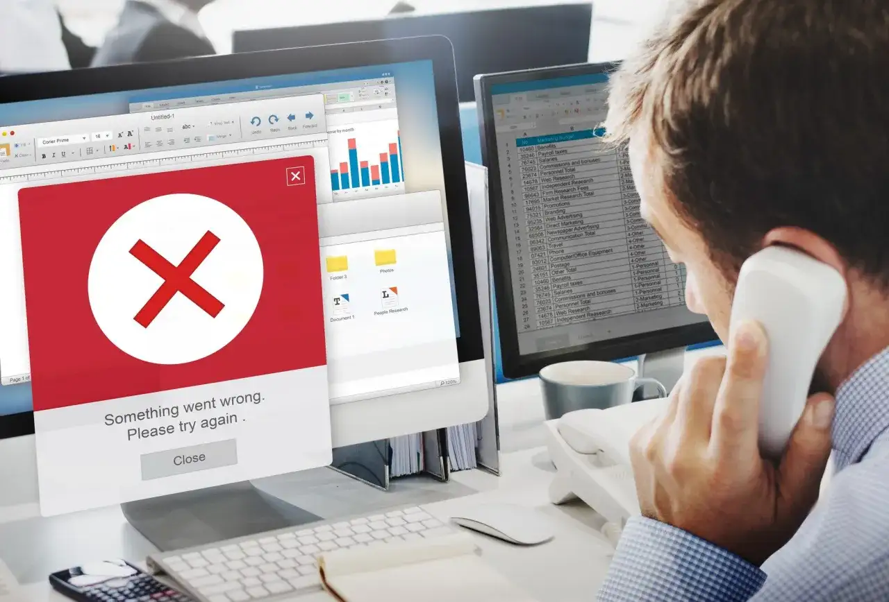 Błąd na ekranie komputera. Mężczyzna rozmawia przez telefon, próbując dowiedzieć się, jak usunąć się z administratora strony na FB.