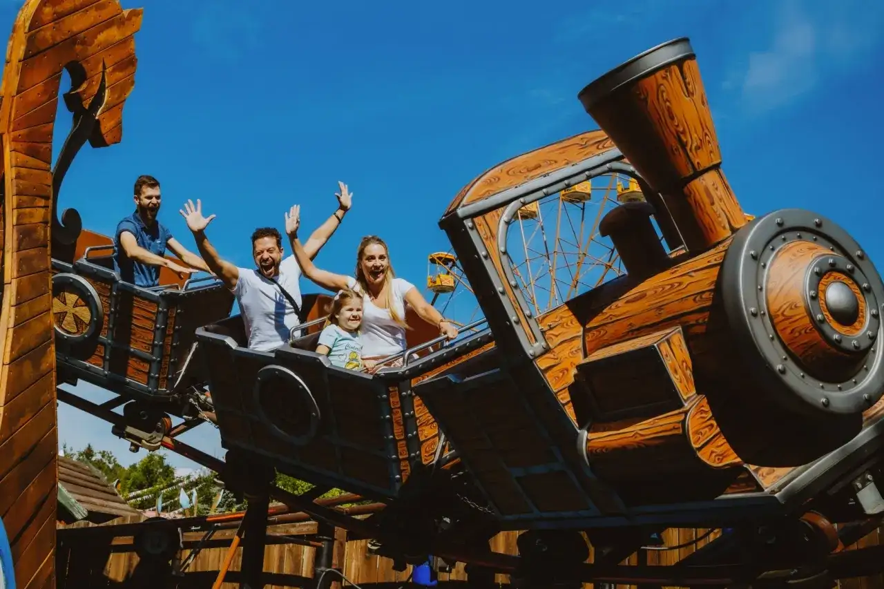 Rodzina na drewnianym rollercoasterze, który wygląda jak lokomotywa. To jeden z największych rollercoasterów w Europie, zapewniający mnóstwo emocji.