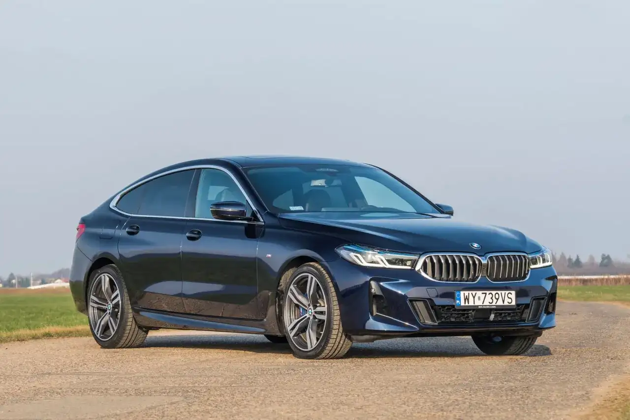 Eleganckie, granatowe BMW 640i na tle pól i błękitnego nieba.