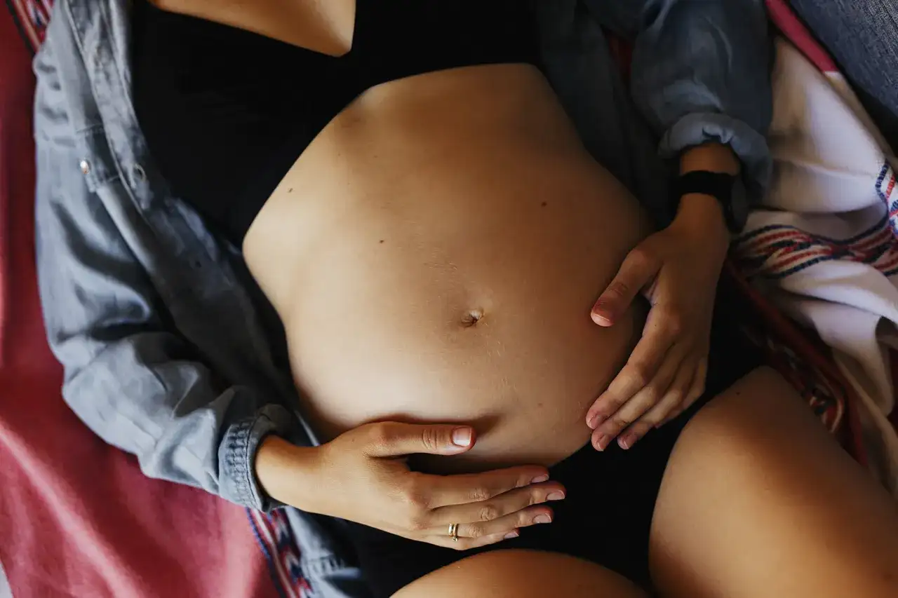 Ciężarna kobieta obejmuje brzuch. Może odczuwać ból pachwin w ciąży, ale skupia się na swoim maleństwie.