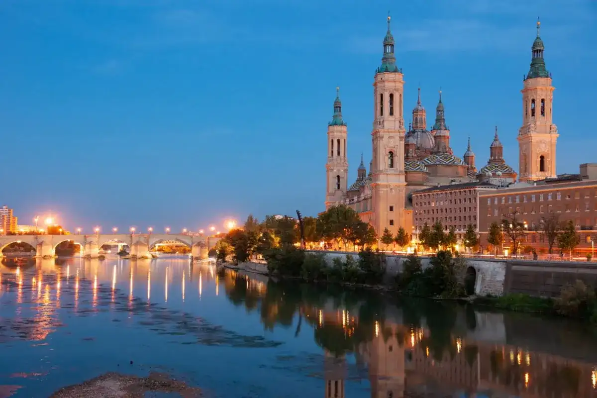 Bazylika w Saragossie i most nad rzeką Ebro o zmierzchu. Idealne miejsce na tanie hiszpania loty.