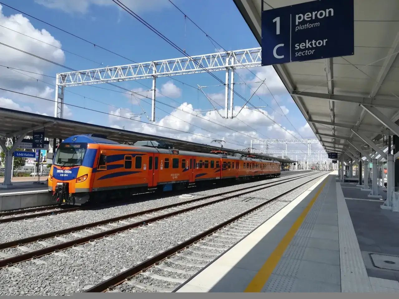 Pociąg Łódź Kaliska - Kołobrzeg PKP na peronie. Nowoczesna stacja, słoneczny dzień.