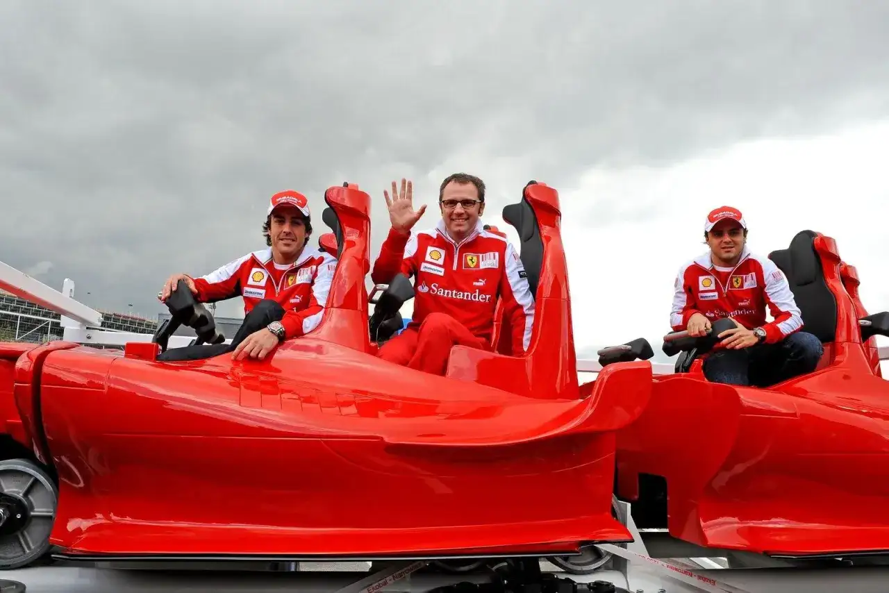 Trzech mężczyzn w strojach Ferrari siedzi w czerwonym wagoniku, który wygląda jak najszybszy rollercoaster na świecie.
