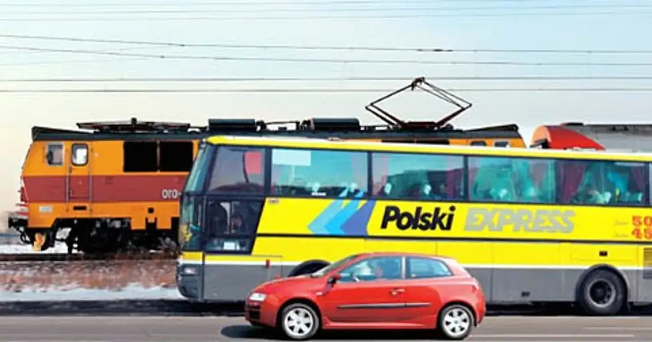 Pociąg, żółty autobus "Polski Express" i czerwony samochód jadą obok siebie, jakby na trasie katowice-kraków.