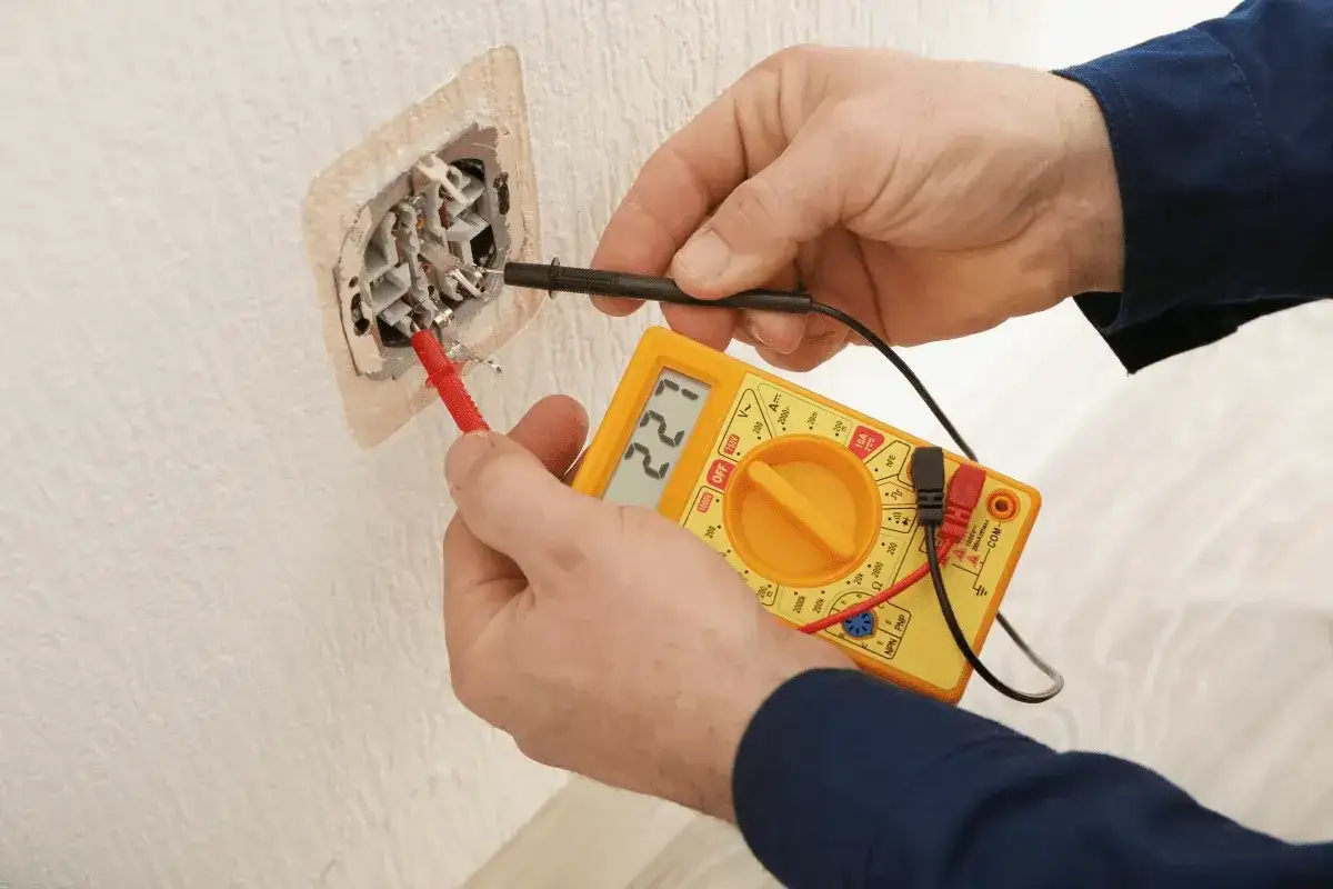 Elektryk mierzy napięcie w gniazdku. Wynik 227V sugeruje, że słaby prąd w domu to nie problem, a prawidłowe działanie instalacji.