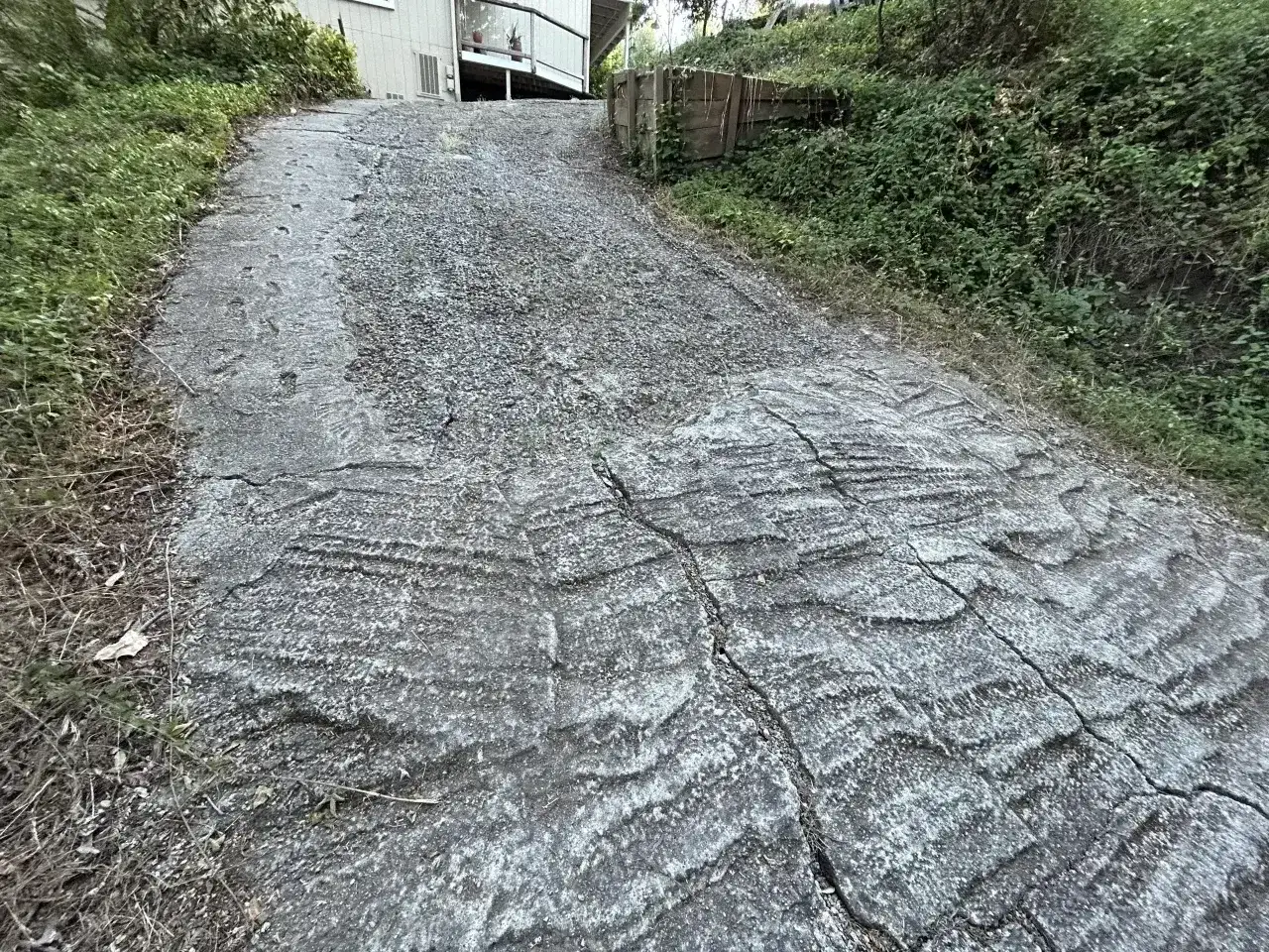 Stromy podjazd z popękanego betonu, z widocznymi śladami po koleinach. Zastanawiasz się, czym wyłożyć stromy podjazd?