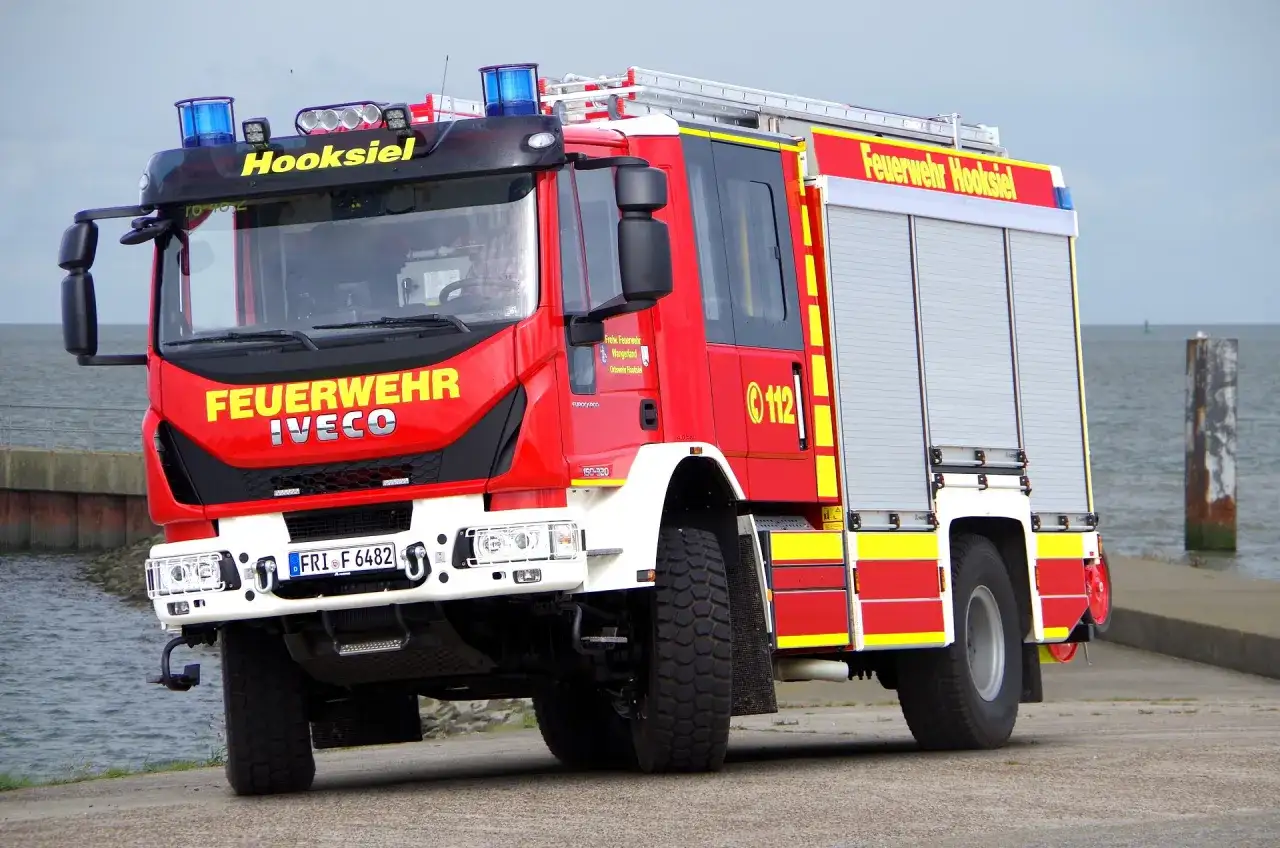 Czerwony wóz strażacki Iveco z napisem "Feuerwehr Hooksiel" i numerem 112. To jeden z rodzajów wozów strażackich, gotowy do akcji.