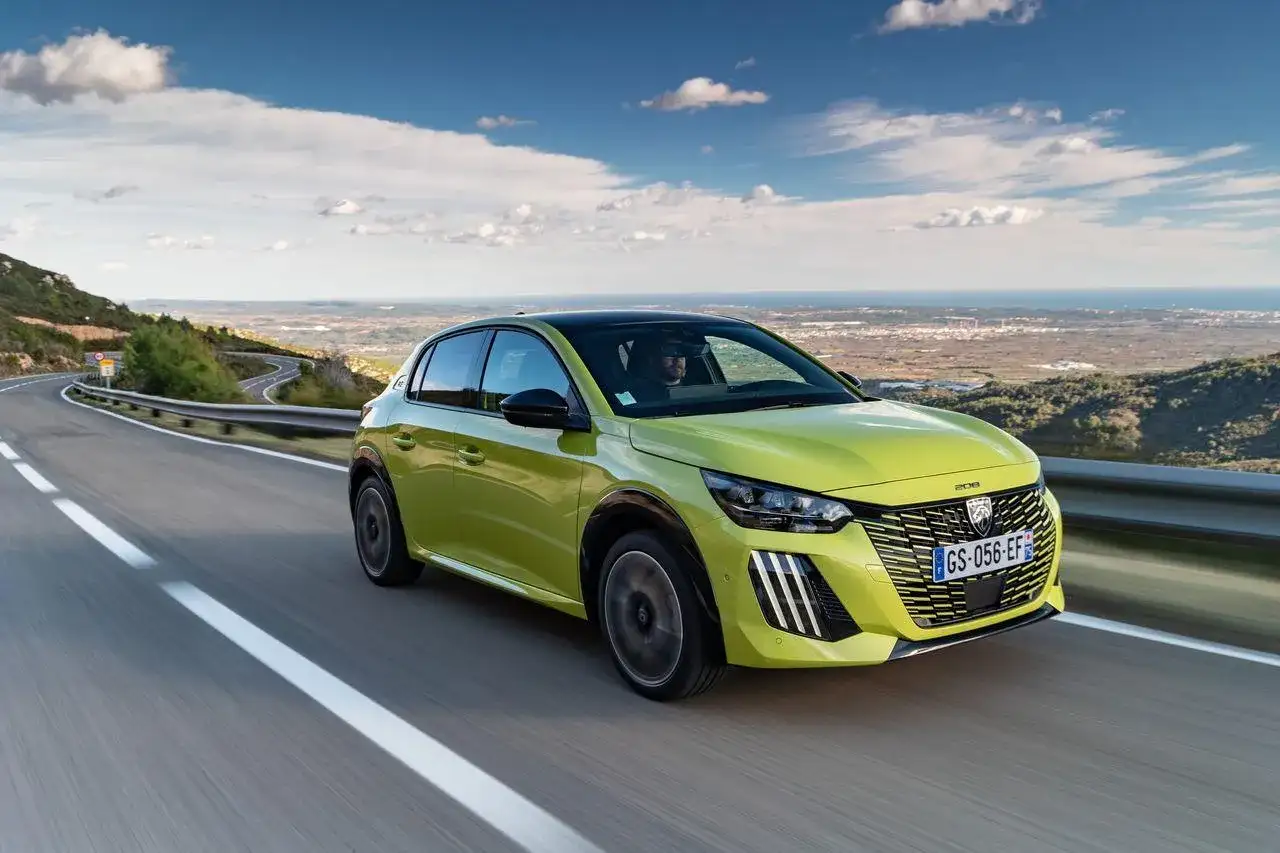 Jaskrawozielony Peugeot 208 na krętej drodze z widokiem na morze. Czy wady i zalety tego modelu skłonią Cię do zakupu?