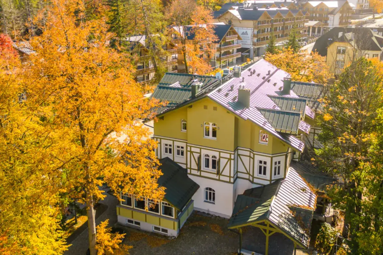 Jesienny hotel w Szklarskiej Porębie otoczony złotymi drzewami. Widok z góry na architekturę górską.