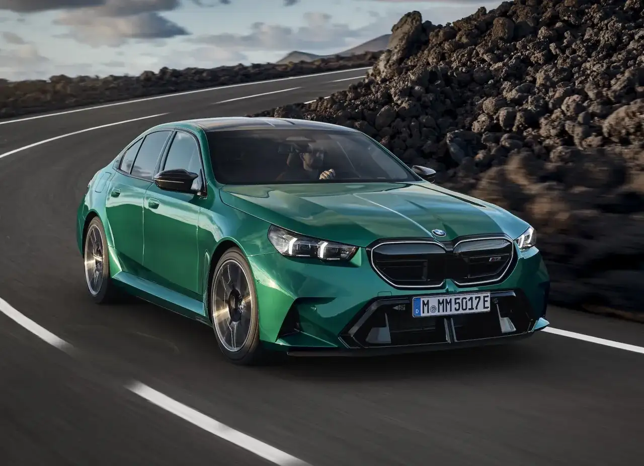 Zielone m5 bmw pędzi po krętej drodze wśród skalistych krajobrazów.