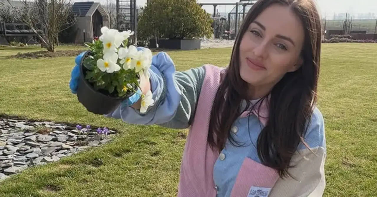 Uśmiechnięta Ania Bardowska, która ma 30 lat, sadzi kwiaty w ogrodzie.