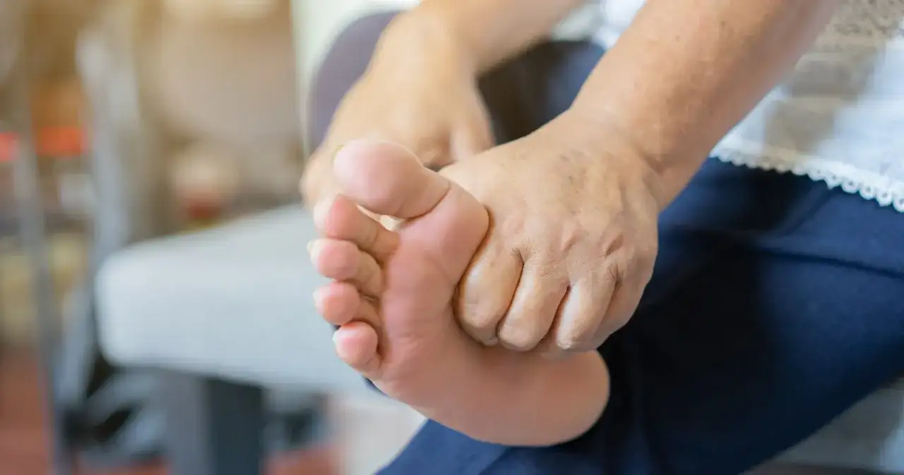 Dłoń masuje stopę, co może być jednym z objawów nadmiaru potasu.
