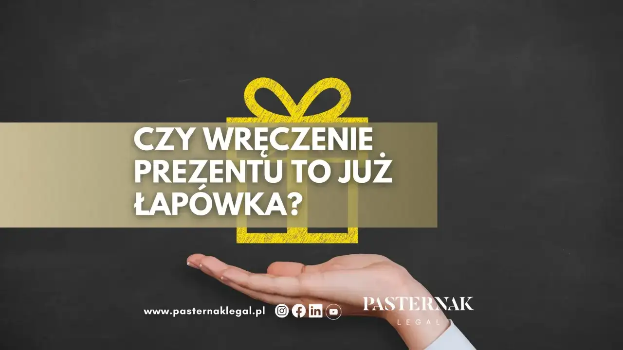 Czy wręczenie prezentu to już łapówka? Dłoń trzyma symbol prezentu, a tekst pyta o granicę między gestem a nielegalnym działaniem.