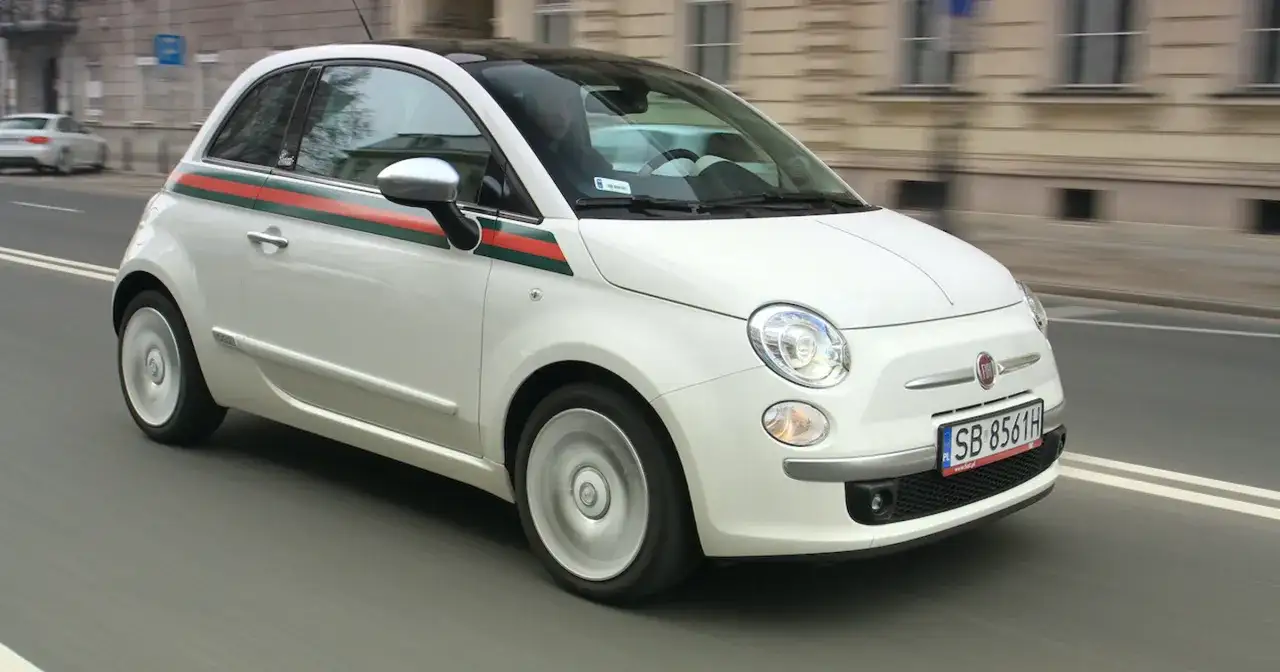Biały Fiat 500 1.2 z zielono-czerwonym pasem na boku, w ruchu miejskim.