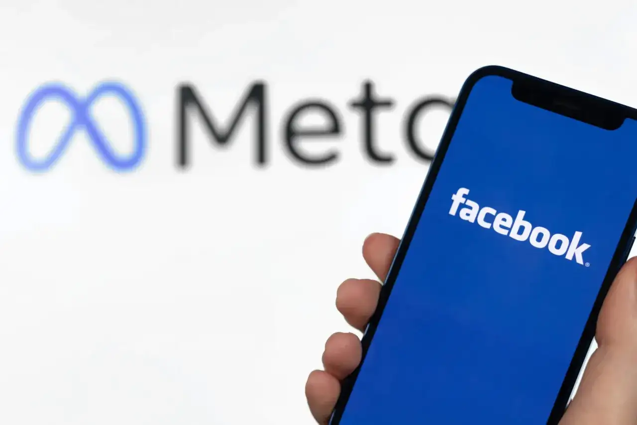 Szukasz sposobu, jak znaleźć osobę na FB po imieniu? Smartfon z logo Facebooka i symbolem Meta w tle.
