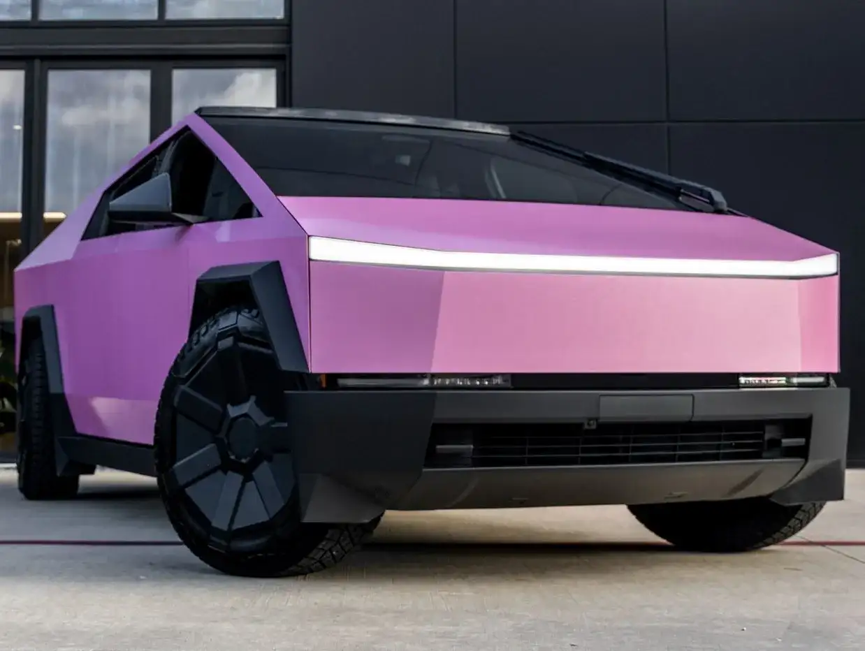 Różowy CyberTruck z futurystycznym designem i masywnymi kołami.