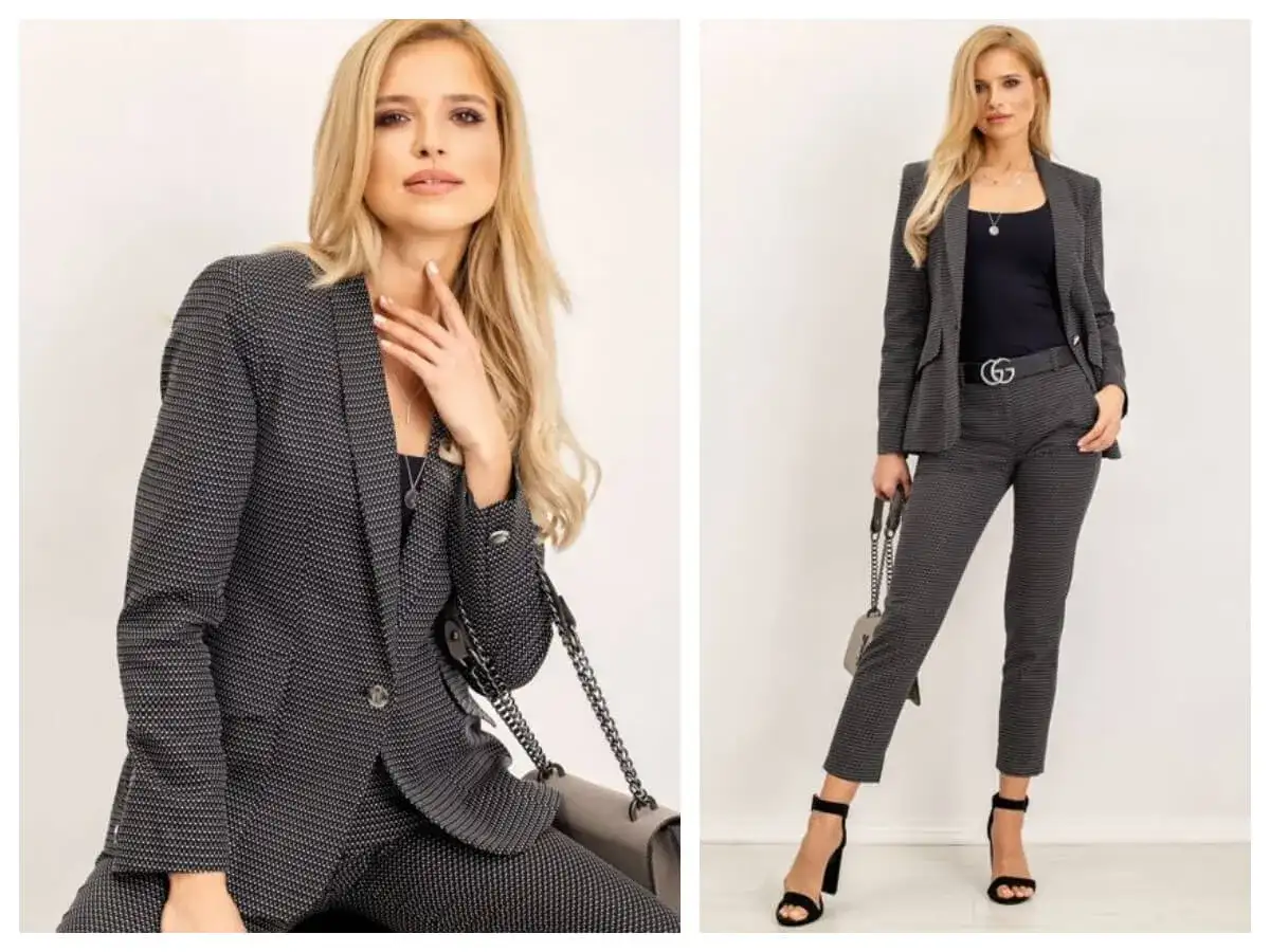 Elegancki damski casual dress code: kobieta w grafitowym garniturze w drobny wzór, z czarną bluzką i torebką.