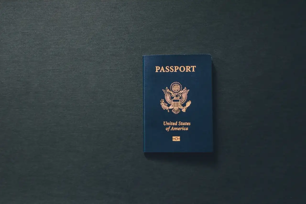 Niebieski paszport USA leży na ciemnym tle. Dokument przypomina o tym, ile ważny jest paszport dla podróżujących.