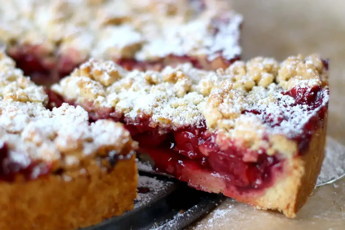 Saftiger Kirschkuchen mit Streuseln, bestäubt mit Puderzucker. Ein köstliches Kirschkuchen Rezept zum Nachbacken.
