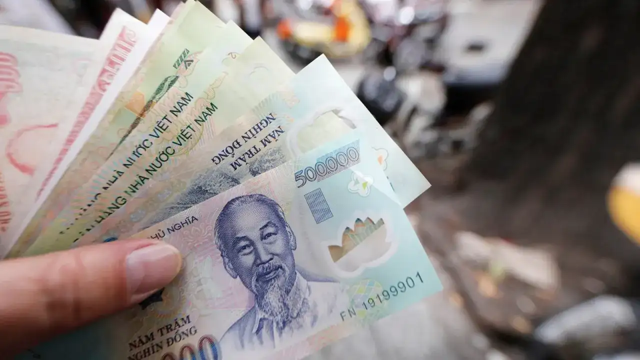 Dłoń trzyma stos banknotów, w tym 500 000 dongów, waluta w Hanoi.