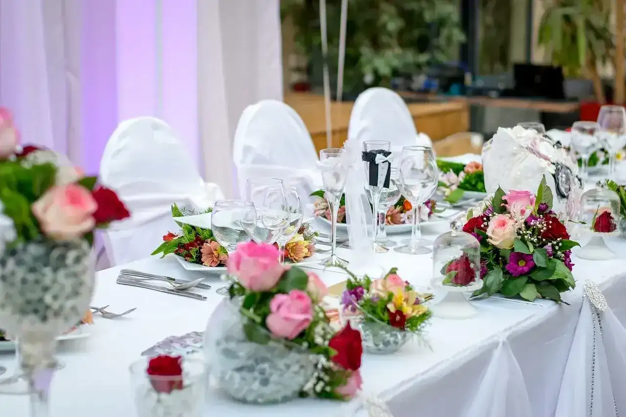 Elegancko nakryty stół weselny z bukietami róż i goździków. Idealne pomysły na wesele, pełne romantyzmu i stylu.