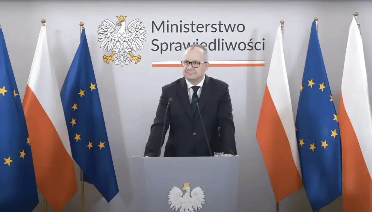 Minister sprawiedliwości przemawia na tle flag Polski i UE. Tematem dyskusji jest ustawa frankowa.