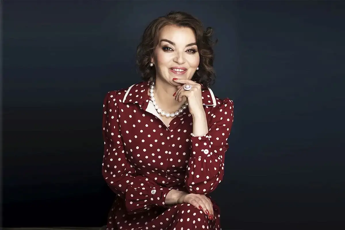 Uśmiechnięta kobieta w sukience w białe kropki, niczym z lat 50. Jej styl to klasyczna polka.