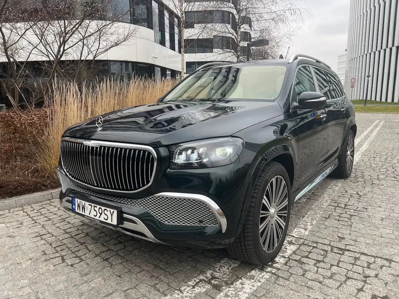Elegancki, czarny GLS Maybach lśni na tle nowoczesnej architektury.