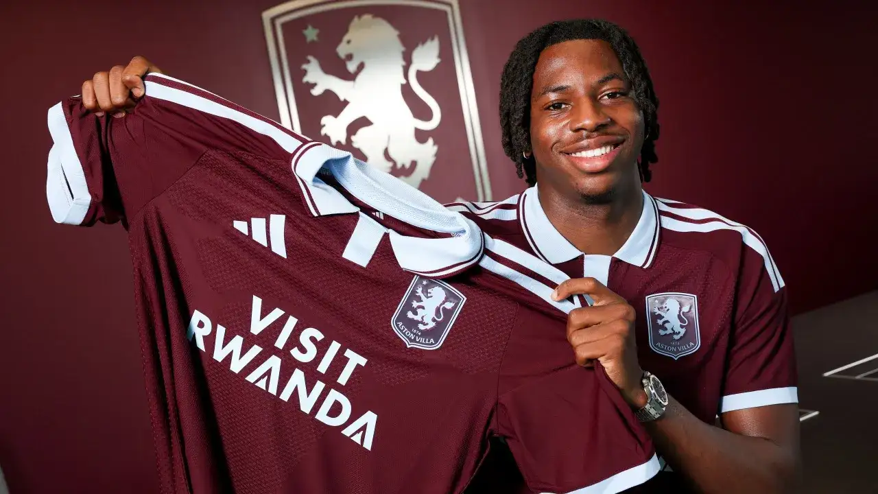 Uśmiechnięty piłkarz prezentuje nową koszulkę Aston Villa z napisem "Visit Rwanda". To ekscytujące wieści o aston villa transfery!